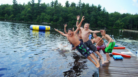 Scouts at waterfront jumping into lake